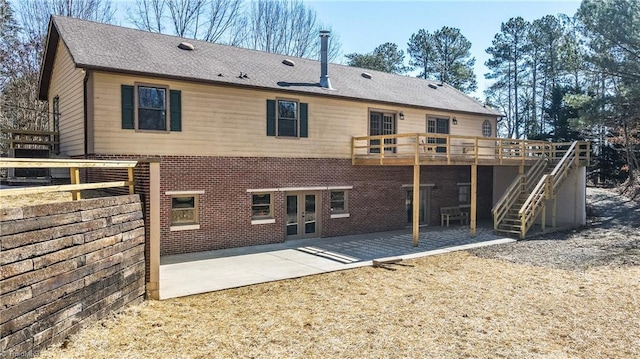 rear view of house featuring a deck, french doors, stairway, brick siding, and a patio area