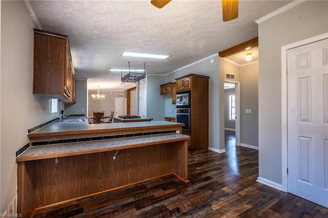 kitchen featuring a peninsula, built in microwave, a sink, black oven, and ceiling fan with notable chandelier