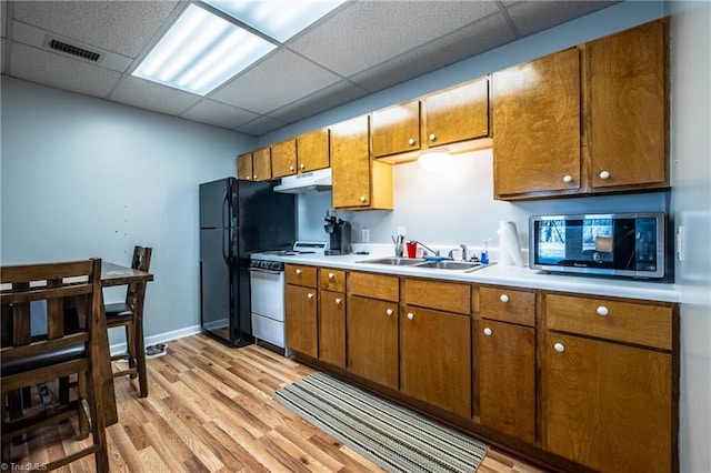 kitchen with brown cabinetry, gas range gas stove, a sink, under cabinet range hood, and stainless steel microwave