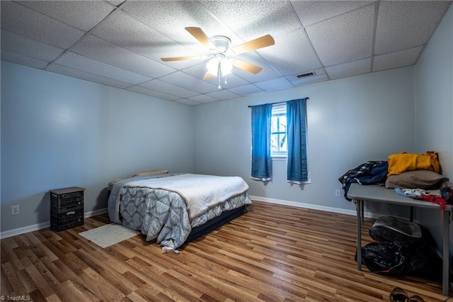 bedroom with visible vents, a paneled ceiling, baseboards, and wood finished floors