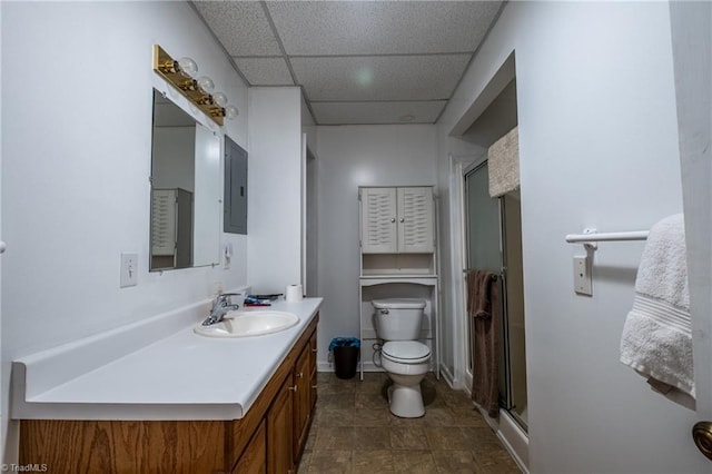 bathroom featuring toilet, electric panel, a stall shower, vanity, and a paneled ceiling