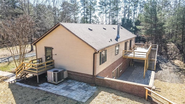 view of side of home with a patio, stairway, central AC unit, a deck, and brick siding