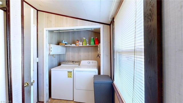 washroom featuring ornamental molding, wooden walls, washer and clothes dryer, cabinets, and light hardwood / wood-style floors