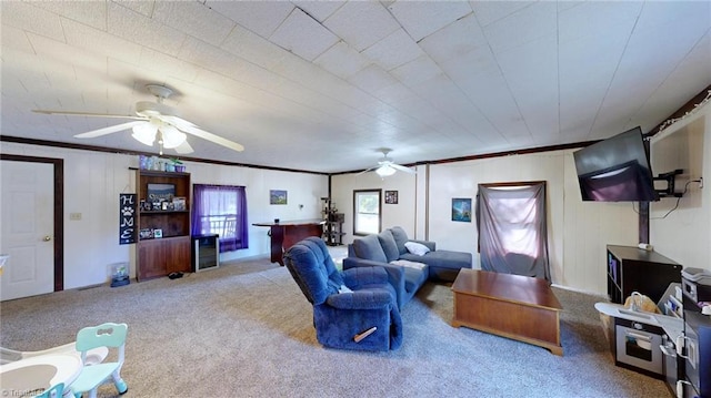 carpeted living room with ceiling fan and ornamental molding