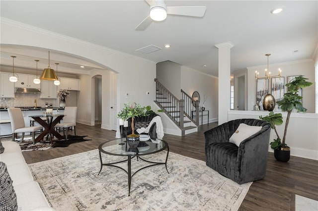 living room with stairs, crown molding, arched walkways, and dark wood-style flooring