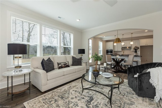 living room with arched walkways, visible vents, crown molding, and wood finished floors