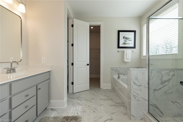 full bathroom featuring a garden tub, marble finish floor, a marble finish shower, baseboards, and vanity