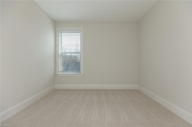 empty room featuring light colored carpet and baseboards