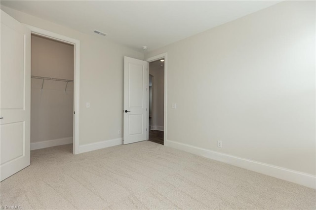 unfurnished bedroom featuring a spacious closet, a closet, baseboards, and carpet floors