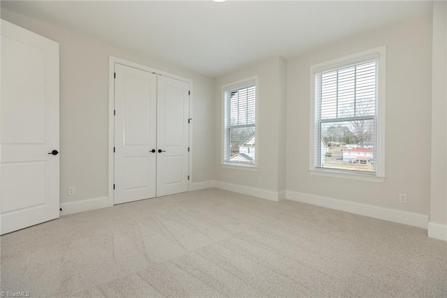 unfurnished bedroom with baseboards, multiple windows, carpet, and a closet