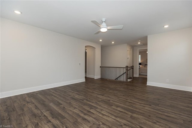 spare room featuring baseboards, dark wood-style floors, recessed lighting, arched walkways, and a ceiling fan