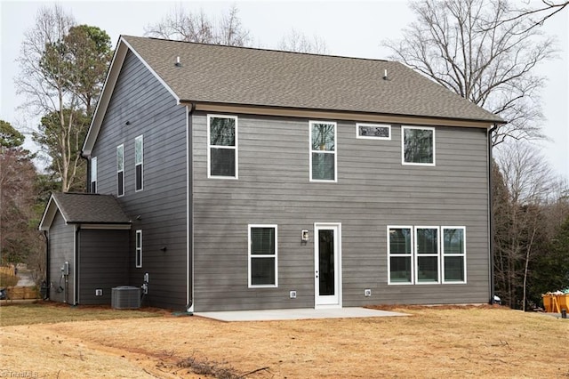 back of house with a lawn, central AC unit, roof with shingles, and a patio area