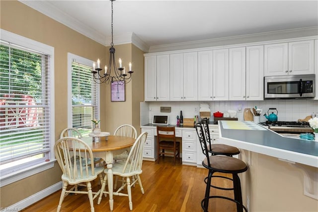 137 Bradford Place Ln, Lewisville, NC 27023 - kitchen featuring stainless steel microwave, light wood-style flooring, decorative backsplash, white cabinetry, and crown molding