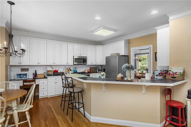 137 Bradford Place Ln, Lewisville, NC 27023 - kitchen featuring stainless steel appliances, a kitchen breakfast bar, a chandelier, a peninsula, and ornamental molding