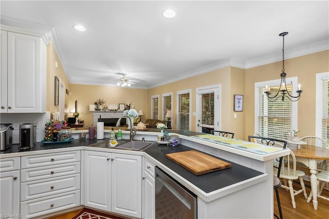 137 Bradford Place Ln, Lewisville, NC 27023 - kitchen featuring a chandelier, dark countertops, a peninsula, crown molding, and white cabinets
