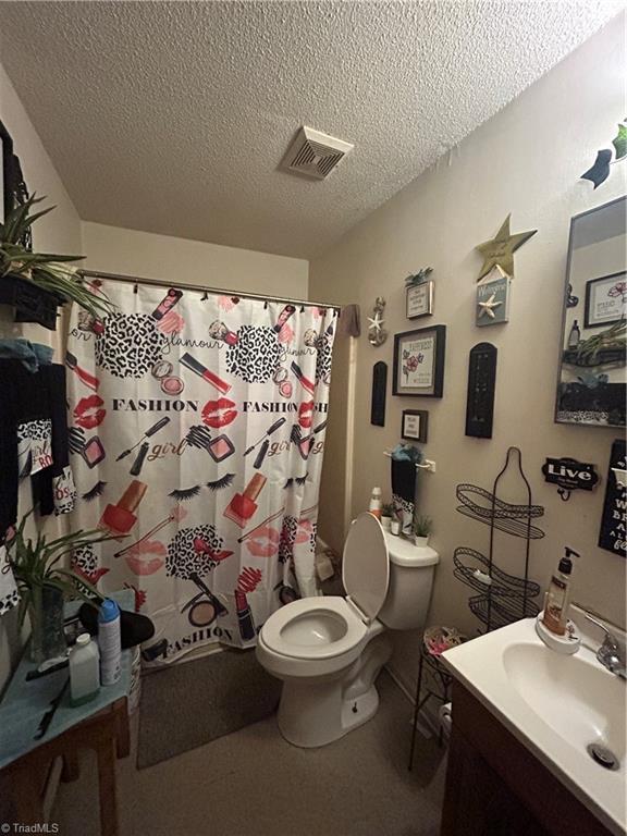 717 Dale St, Greensboro, NC 27406 - bathroom with a textured ceiling, toilet, vanity, and curtained shower
