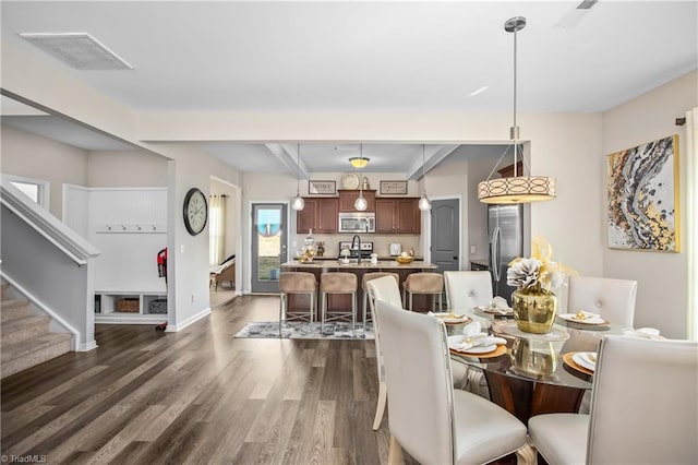 dining area featuring beamed ceiling, dark hardwood / wood-style floors, and sink