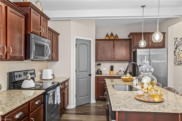 kitchen featuring sink, stainless steel appliances, backsplash, an island with sink, and decorative light fixtures