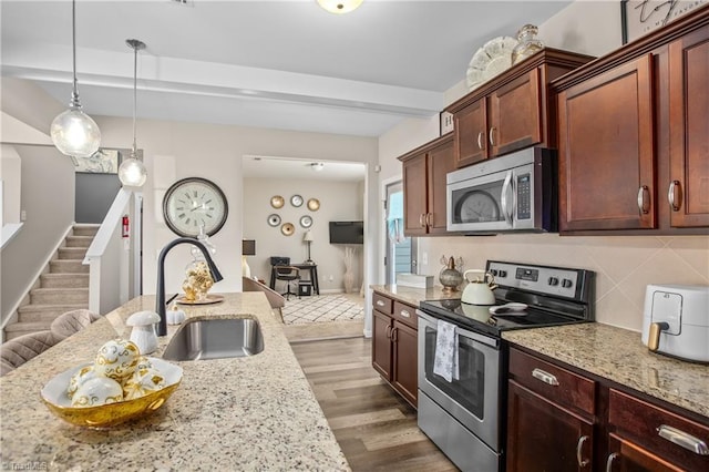 kitchen with sink, appliances with stainless steel finishes, tasteful backsplash, decorative light fixtures, and light stone counters