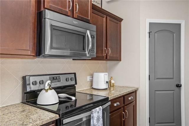 kitchen with decorative backsplash, electric range oven, and light stone counters