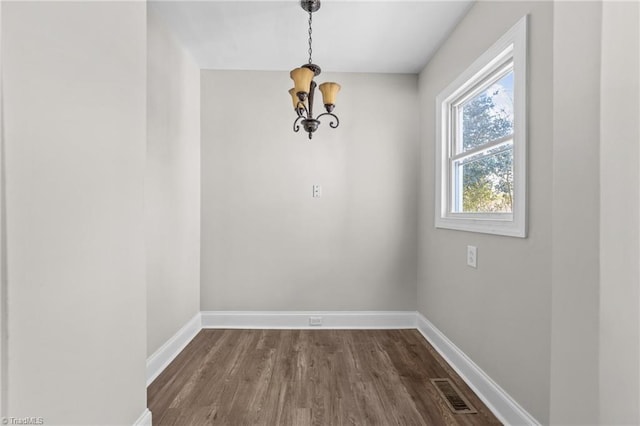 unfurnished dining area with hardwood / wood-style floors and a chandelier