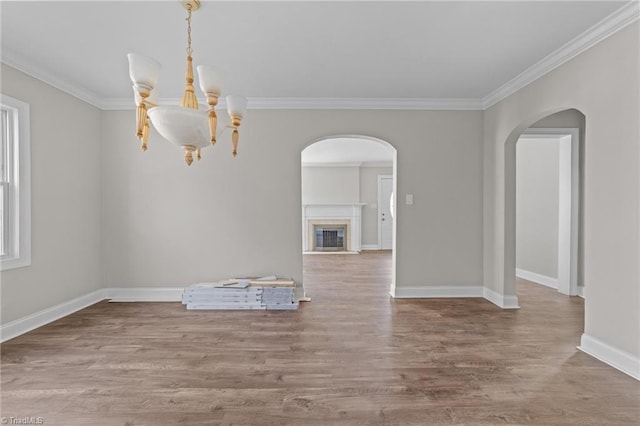 unfurnished dining area with wood-type flooring, ornamental molding, and a notable chandelier