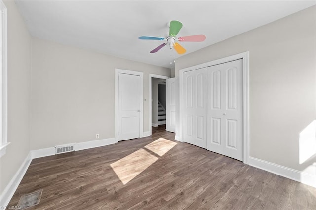 unfurnished bedroom featuring ceiling fan, dark wood-type flooring, and a closet