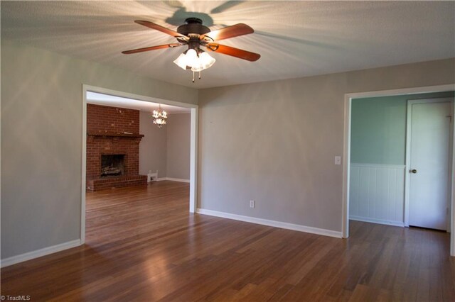 159 Evans Ln, Wilkesboro, NC 28697 - unfurnished living room featuring ceiling fan with notable chandelier, a fireplace, dark wood finished floors, and baseboards