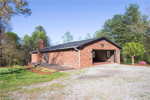 159 Evans Ln, Wilkesboro, NC 28697 - view of property exterior with a garage, brick siding, a chimney, and a lawn