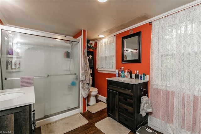 bathroom with ornamental molding, vanity, hardwood / wood-style flooring, toilet, and a shower with shower door