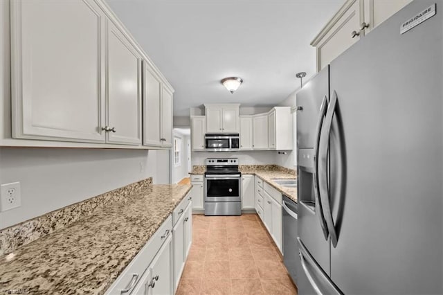 465 NC Highway 42 S, Asheboro, NC 27205 - kitchen featuring appliances with stainless steel finishes, light stone countertops, white cabinetry, light tile patterned floors, and a sink