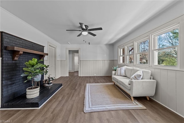 living area featuring a ceiling fan, wainscoting, and wood finished floors