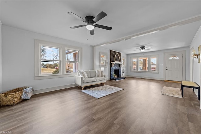 unfurnished room featuring a fireplace, wood finished floors, a ceiling fan, and baseboards