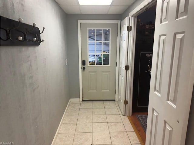 doorway with light tile patterned flooring and a drop ceiling