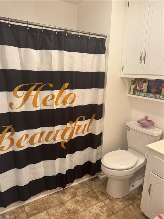 bathroom featuring vanity, curtained shower, and toilet