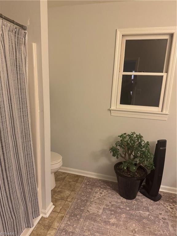 bathroom with toilet and a shower with shower curtain