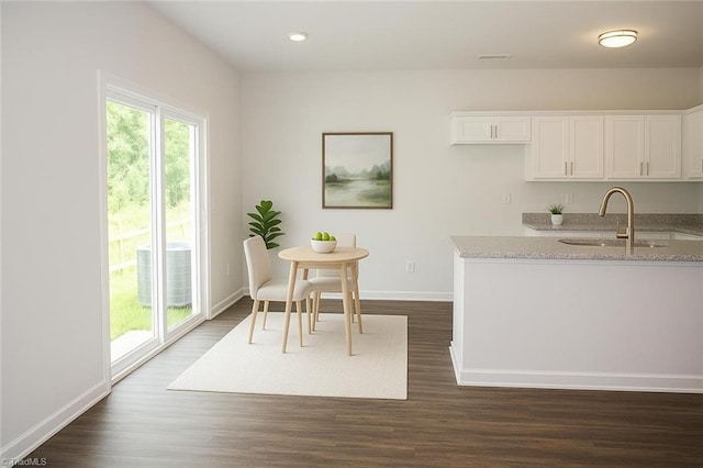 1100 Brooksridge Way, Whitsett, NC 27377 - kitchen featuring a sink, white cabinets, dark wood-style flooring, light stone countertops, and baseboards