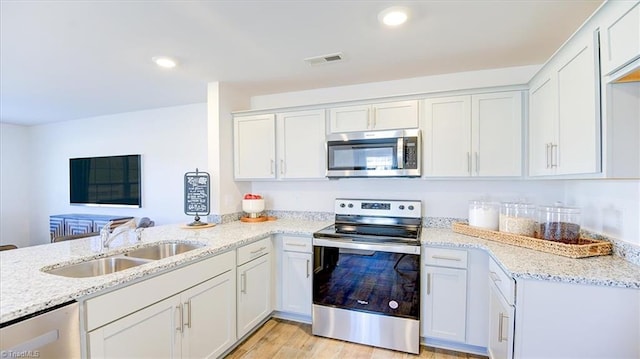 kitchen with a sink, visible vents, light stone countertops, and stainless steel appliances