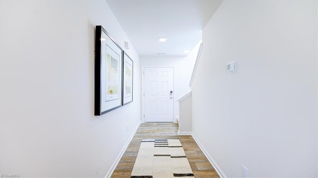 corridor featuring baseboards and light wood-type flooring