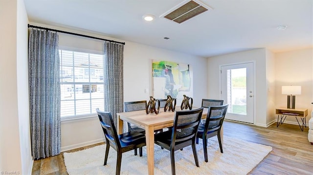 dining room featuring light wood finished floors, visible vents, baseboards, and a healthy amount of sunlight