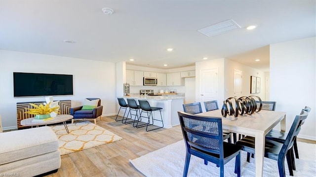 dining area featuring light wood finished floors, baseboards, and recessed lighting