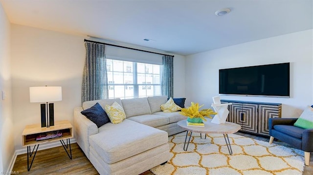 living area featuring visible vents, baseboards, and wood finished floors