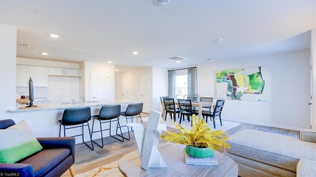 living area with recessed lighting, visible vents, baseboards, and light wood-style flooring