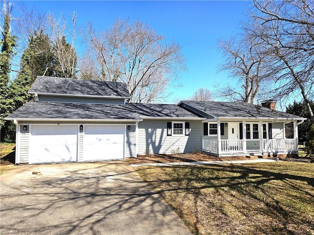 view of front of home with a front lawn, covered porch, a chimney, a garage, and driveway