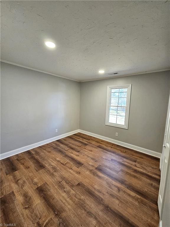 empty room featuring baseboards, a textured ceiling, dark wood-style flooring, and crown molding