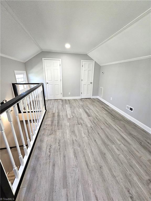 bonus room featuring lofted ceiling, wood finished floors, visible vents, and baseboards