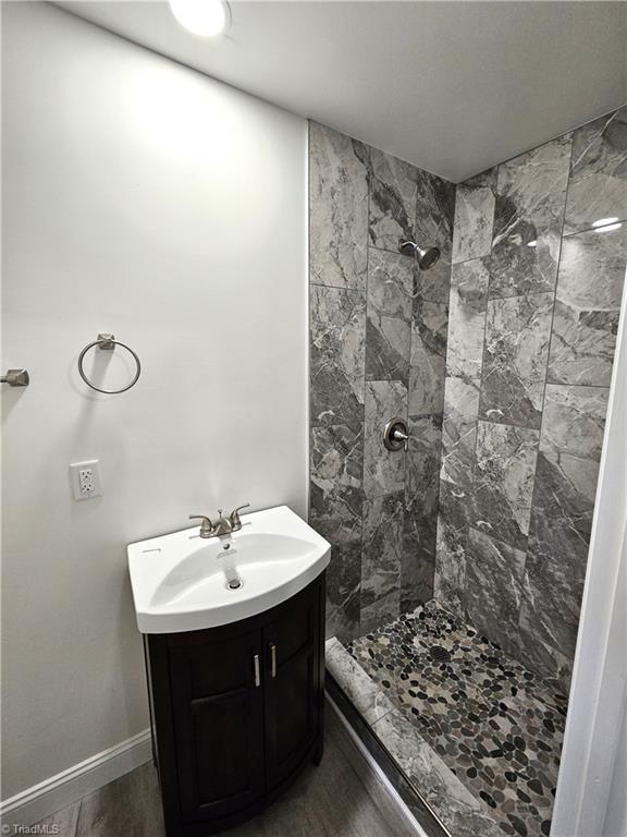 full bath with vanity, a shower stall, wood finished floors, and baseboards