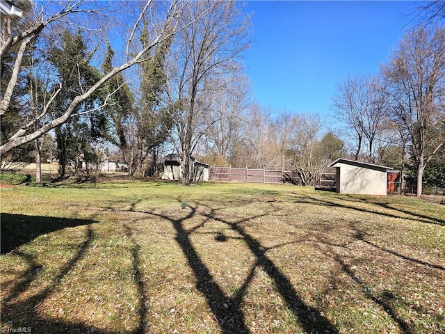 view of yard featuring an outbuilding, a storage unit, and fence