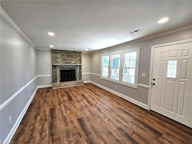 unfurnished living room with baseboards, visible vents, dark wood-style flooring, a stone fireplace, and crown molding