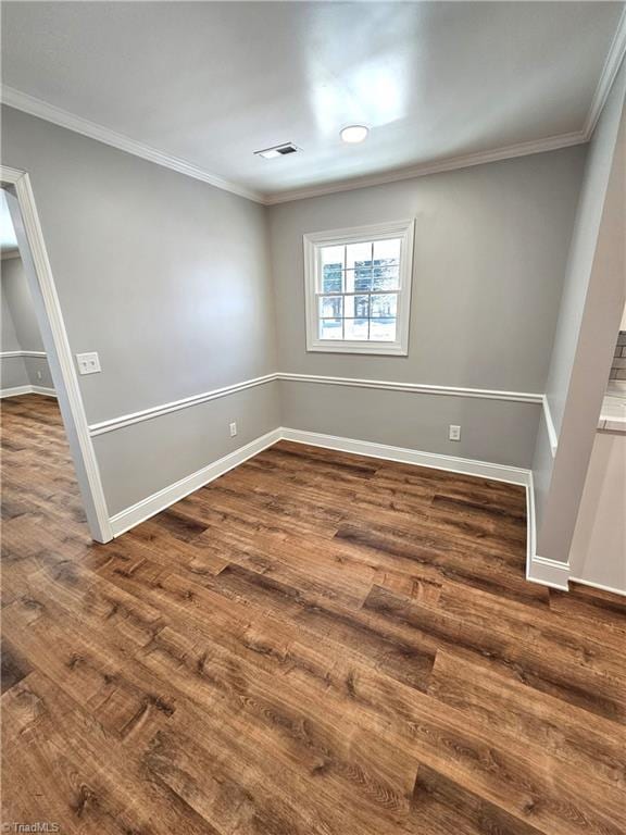 spare room with visible vents, baseboards, dark wood-style floors, and ornamental molding